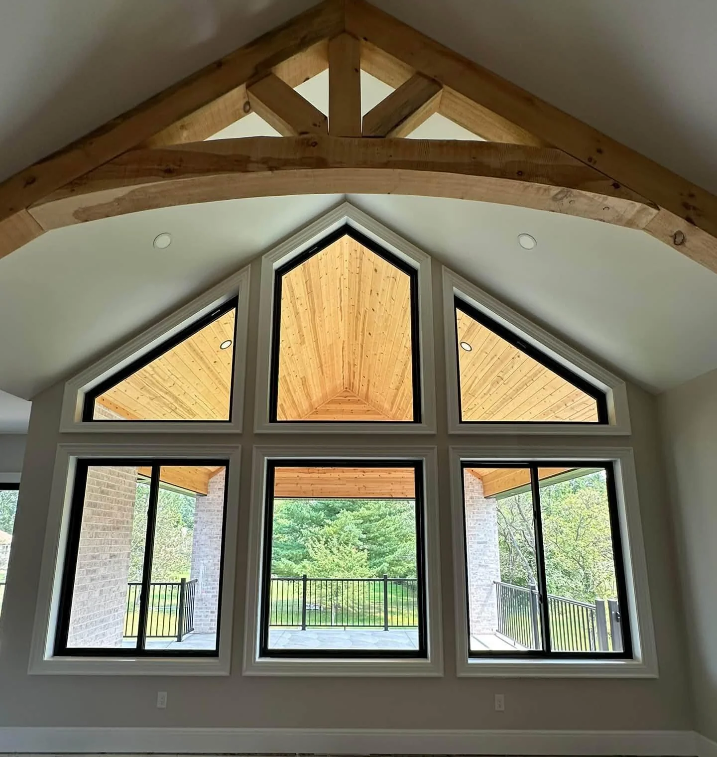 Gabled window arrangement beneath exposed timber beams with a view of a green garden
