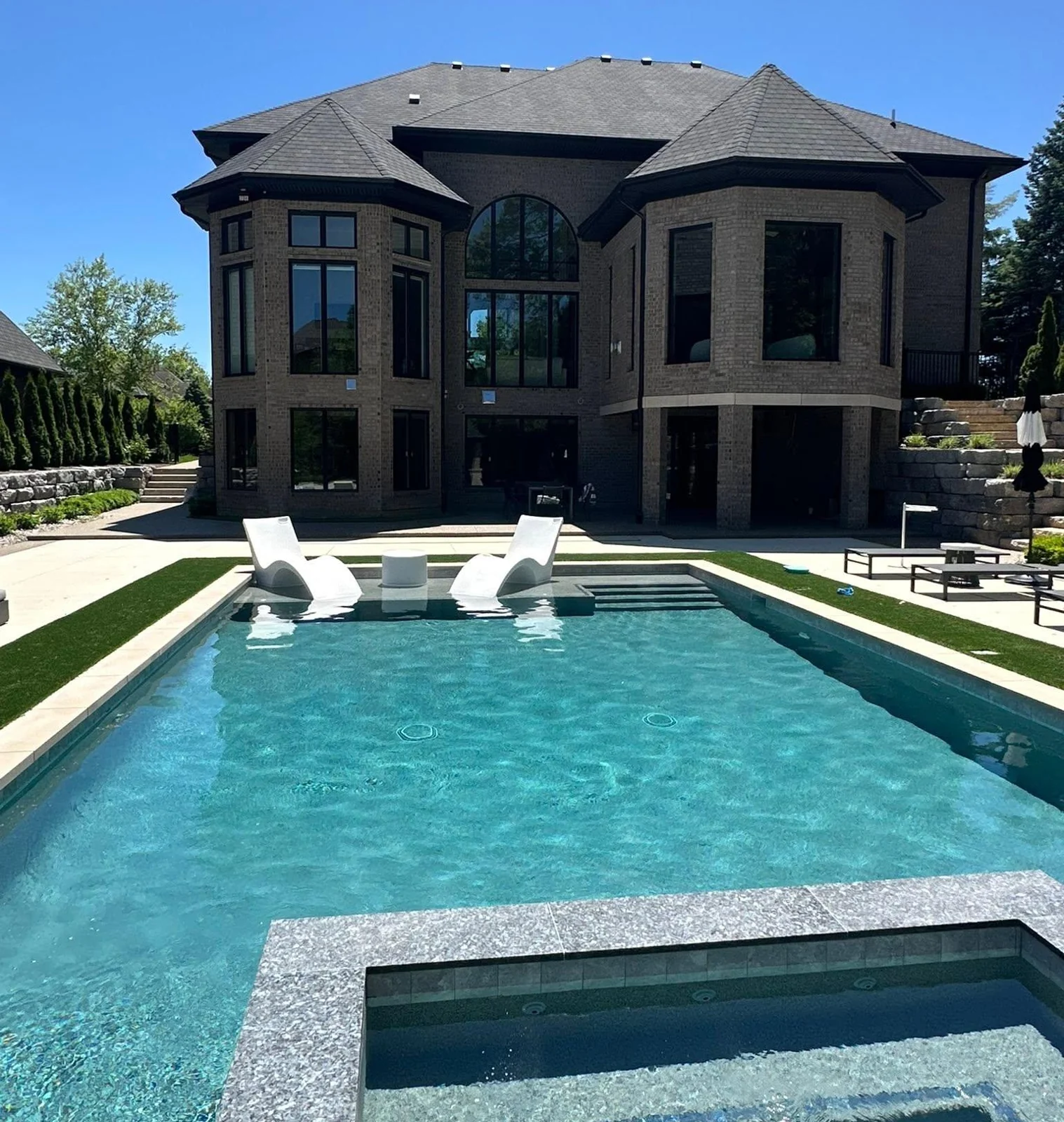 Tall windows and an arched central window overlooking a turquoise swimming pool